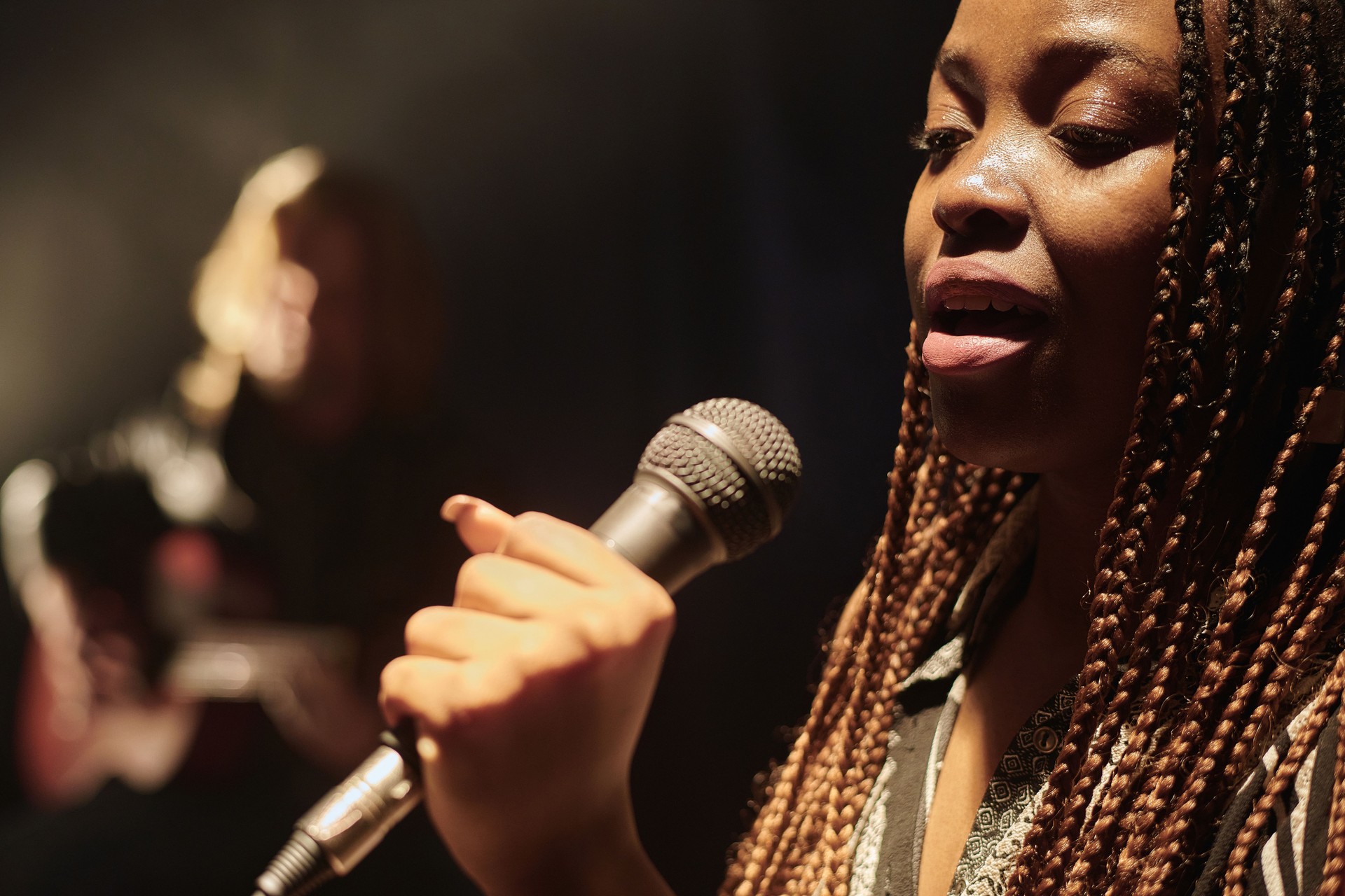 Black Singer Holding Microphone And on Stage in Spotlight